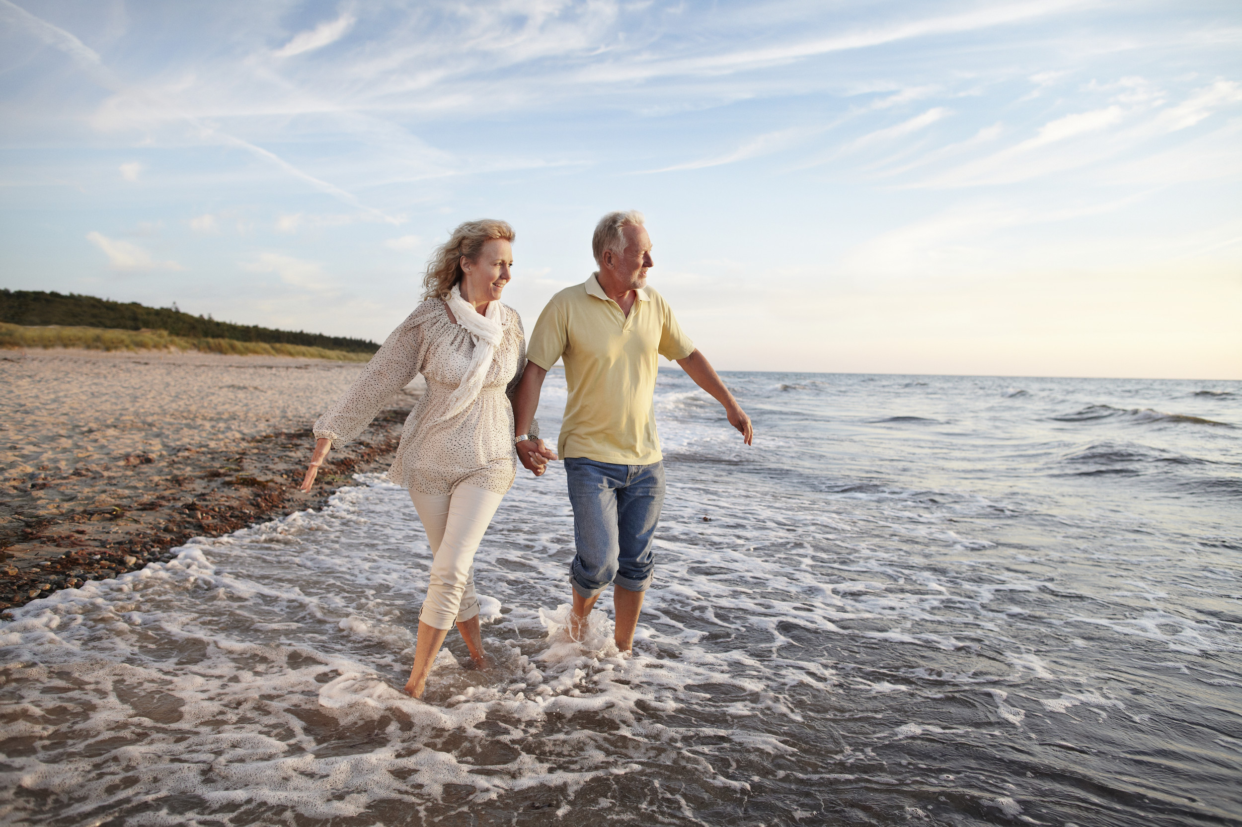 Mature couple paddling in sea looking at sunset
