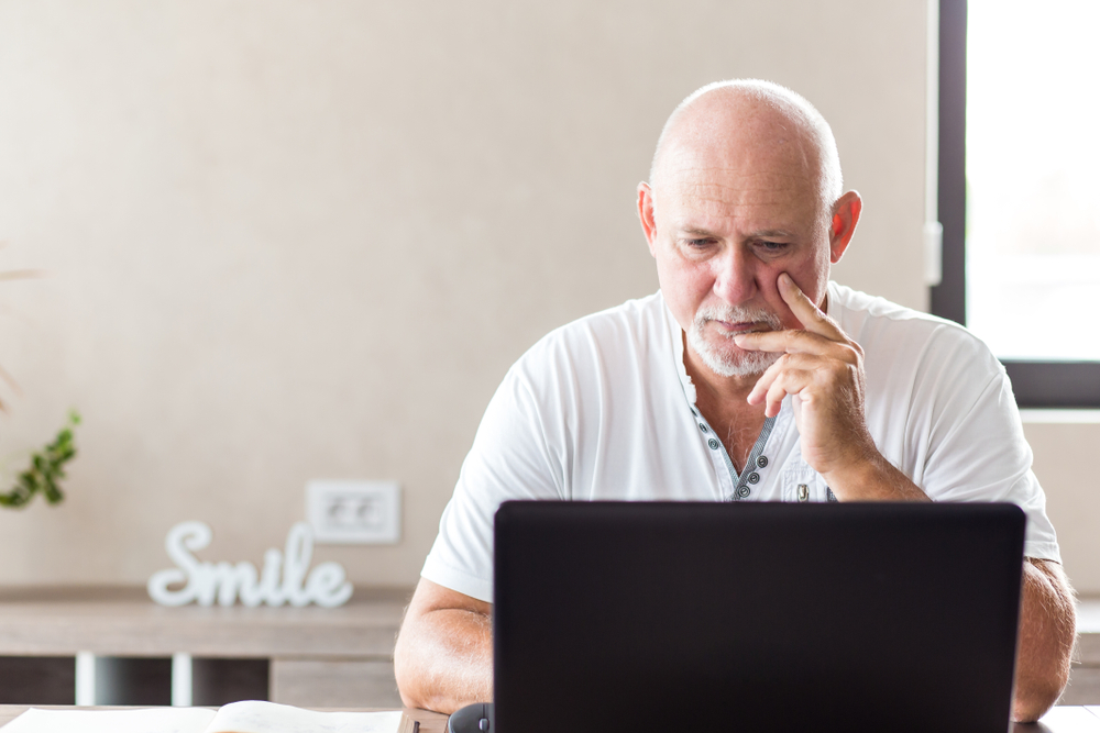 Oudere man werkt op een laptop