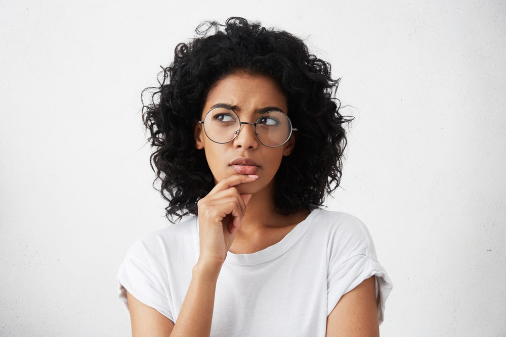 Jonge vrouw met een grote bril heeft een bedenkelijke blik