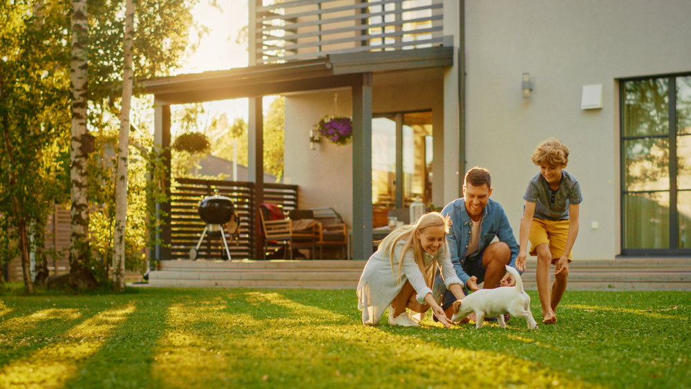 Gezin speelt met een kleine hond in de tuin van hun huis