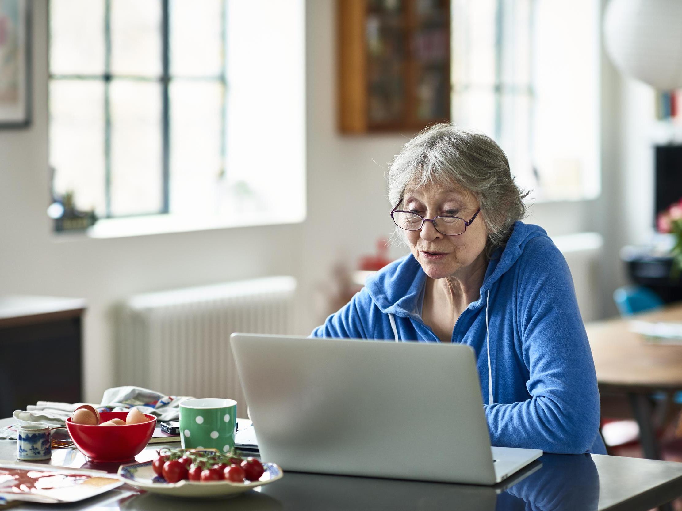 Senior woman wearing glasses using laptop at home