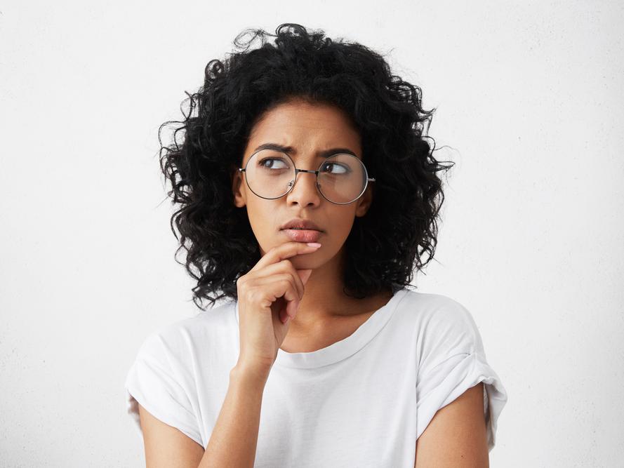 Jonge vrouw met een grote bril heeft een bedenkelijke blik