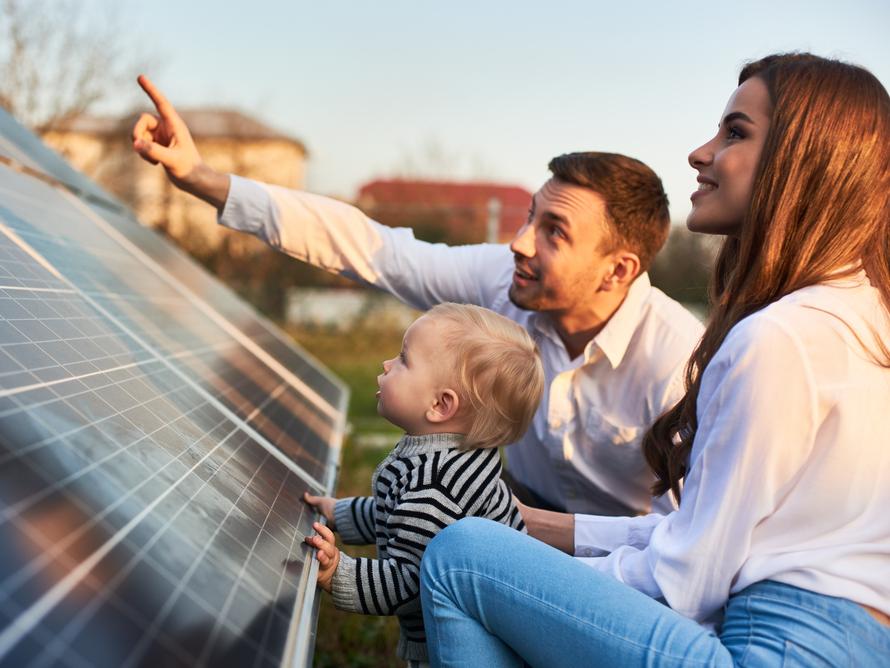 Man en vrouw kijken met een klein kindje naar een zonnepaneel