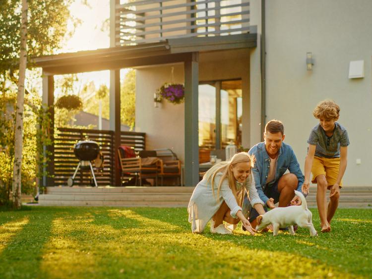 Gezin speelt met een kleine hond in de tuin van hun huis