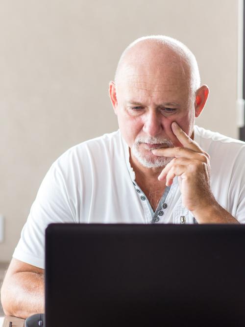 Oudere man werkt op een laptop