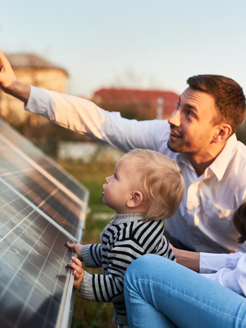 Man en vrouw kijken met een klein kindje naar een zonnepaneel
