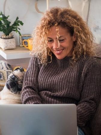 Femme sur l'ordinateur dans le divan avec son chien