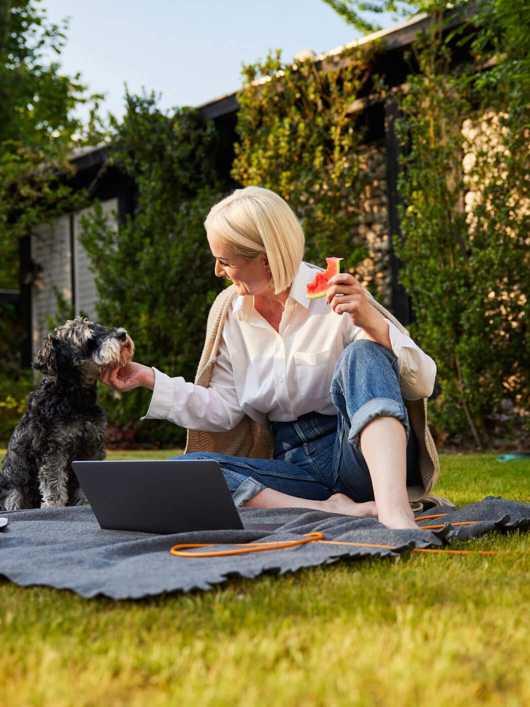 Een oudere dame die tevreden naar haar laptop kijkt, terwijl ze bankiert