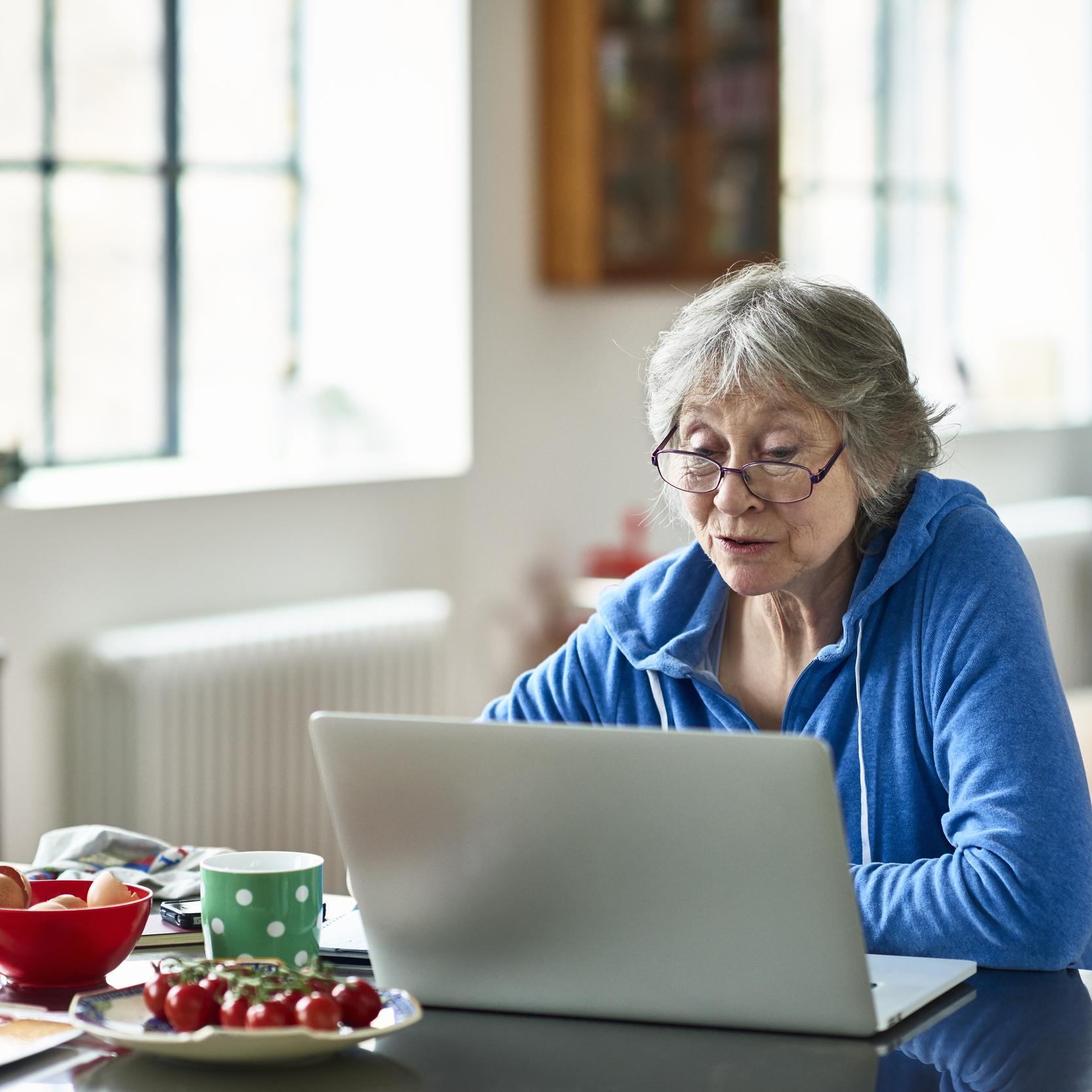 Senior woman wearing glasses using laptop at home