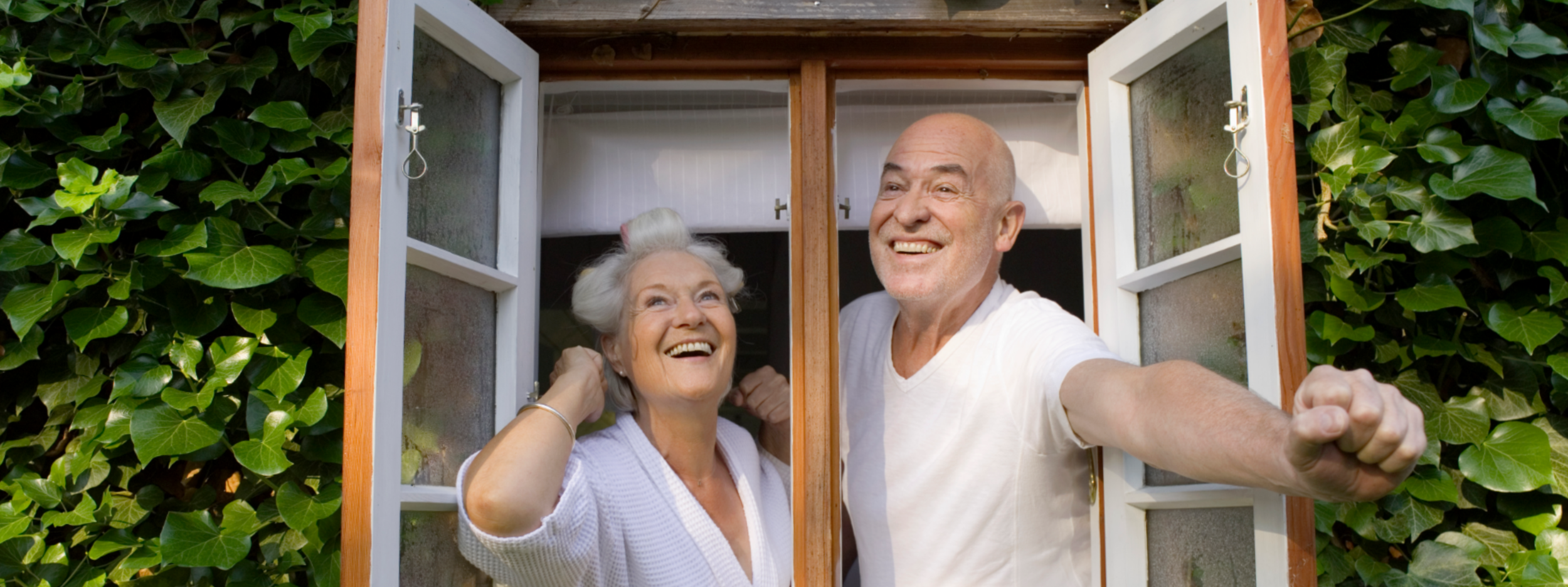 Senior couple opening window in morning, smiling