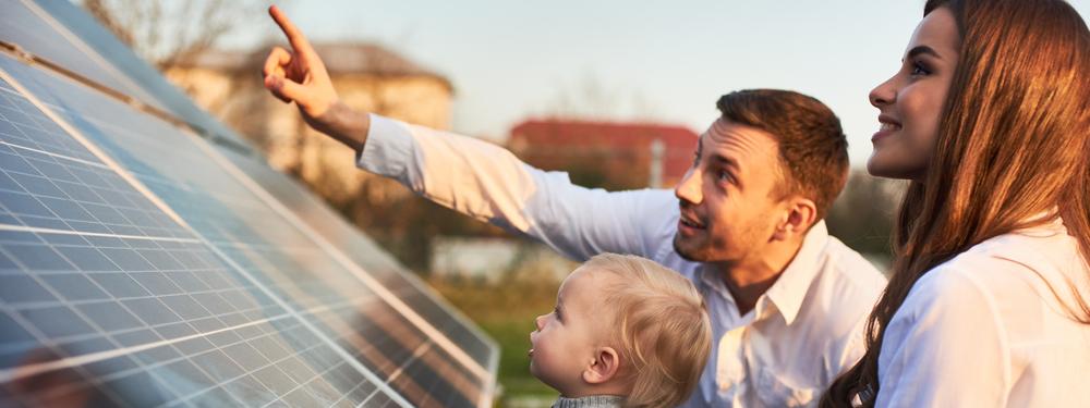 Man en vrouw kijken met een klein kindje naar een zonnepaneel